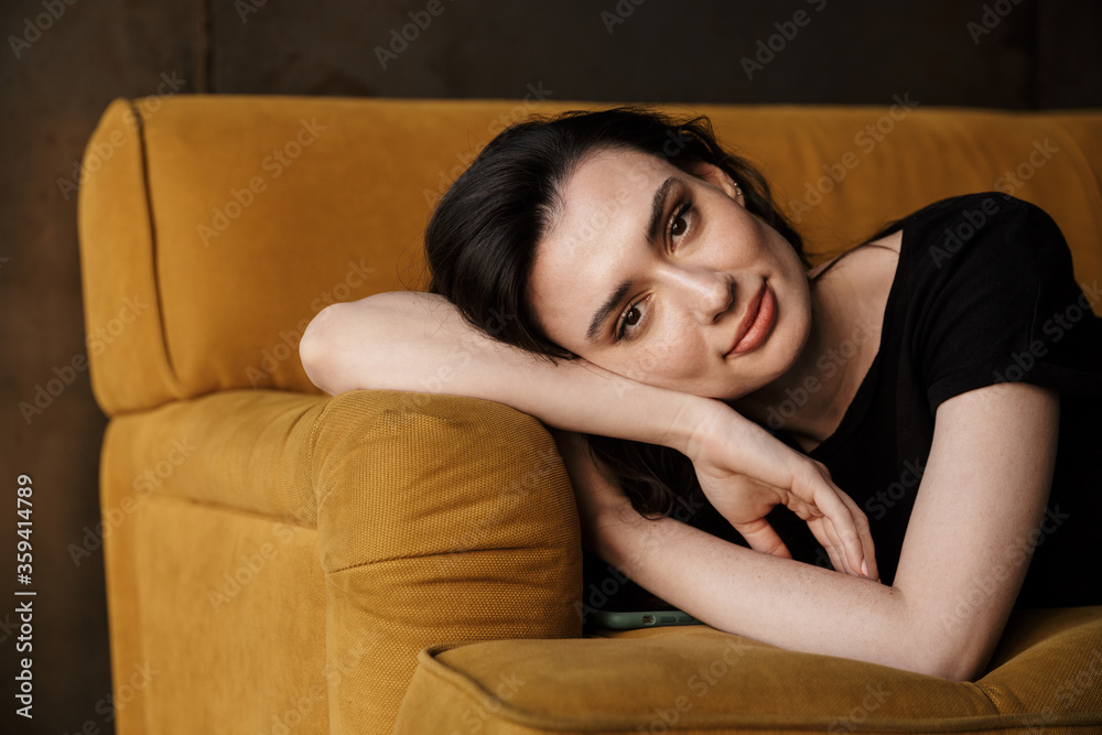 Photo of beautiful young brunette woman lying on couch in apartment Photo of beautiful young brunette woman lying on couch in apartment