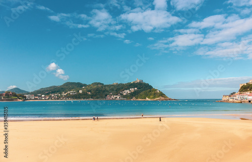 Fototapeta Naklejka Na Ścianę i Meble -  Wide beach of Biscay Bay. San Sebastian landmark, Basque Country, Spain. Scenic coastline with tourists. Promenade along the beach with waves. Travel and recreation concept. Aerial seascape in Europe.