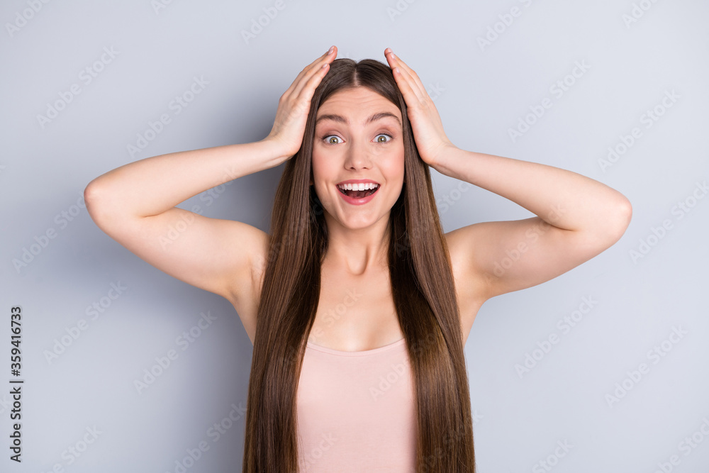 Photo of attractive shocked lady looking mirror ideal neat long healthy hairstyle after salon procedure arms on head not believe eyes wear beige singlet isolated grey color background Photo of attractive shocked lady looking mirror ideal neat long healthy hairstyle after salon procedure arms on head not believe eyes wear beige singlet isolated grey color background