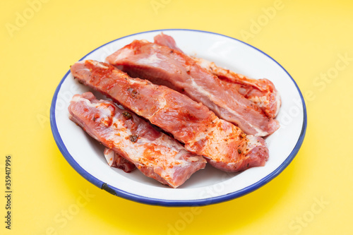 marinated ribs in white dish on yellow background