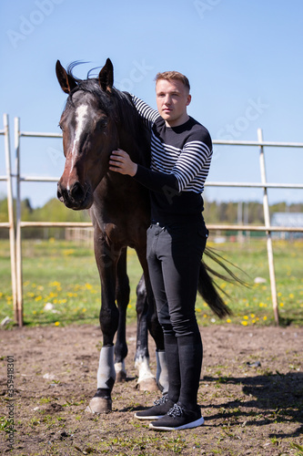 Young horse with man standing on the pasture