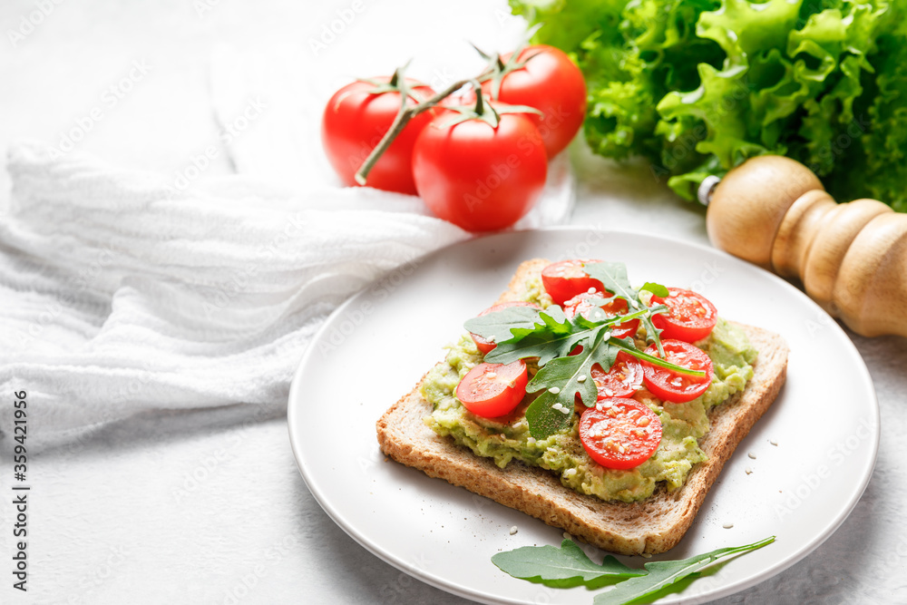 Avocado rye bread toast with cherry tomatoes and arugula