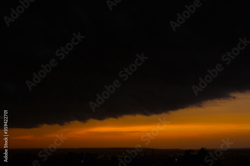 Black thunderclouds at sunset. Bright orange sunset and dark clouds. Storm sky