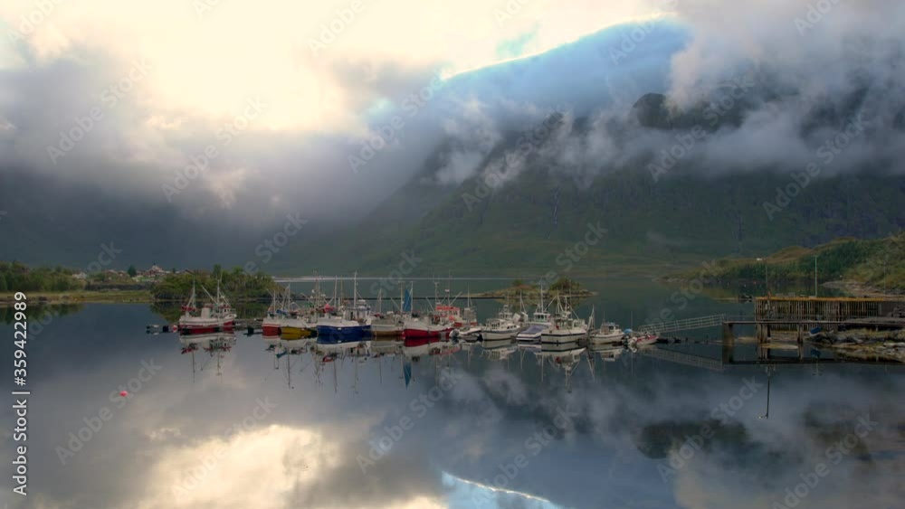 Moored boats and clouds swirling round the mountains, Lofoten Islands, Norway Moored boats and clouds swirling round the mountains, Lofoten Islands, Norway