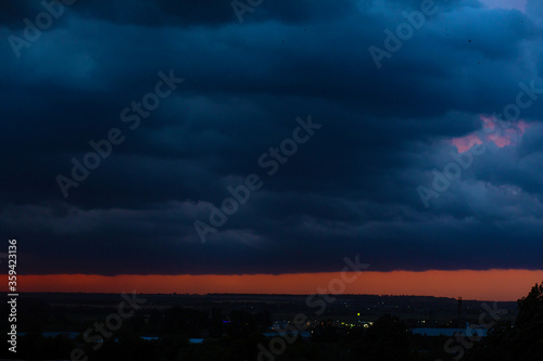 Black thunderclouds at sunset. Bright orange sunset and dark clouds. Storm sky