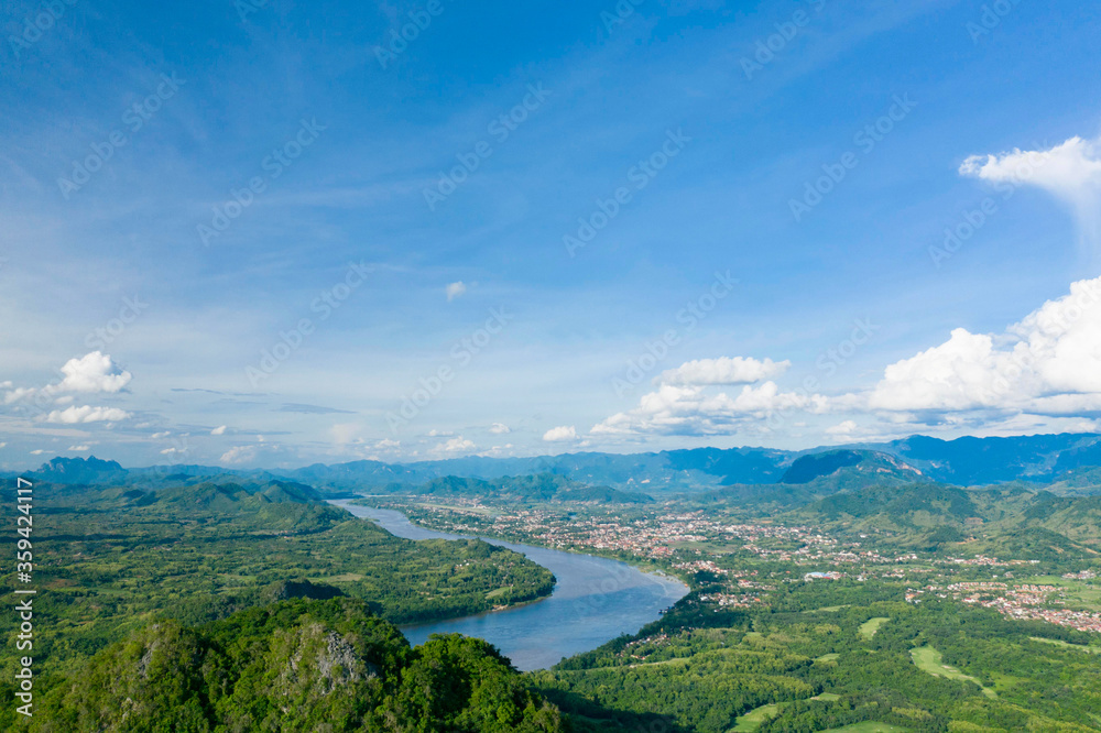 Des nuages surplombent la plaine entourée de montagnes au bord du fleuve Mékong vers Luang Prabang, au Laos.