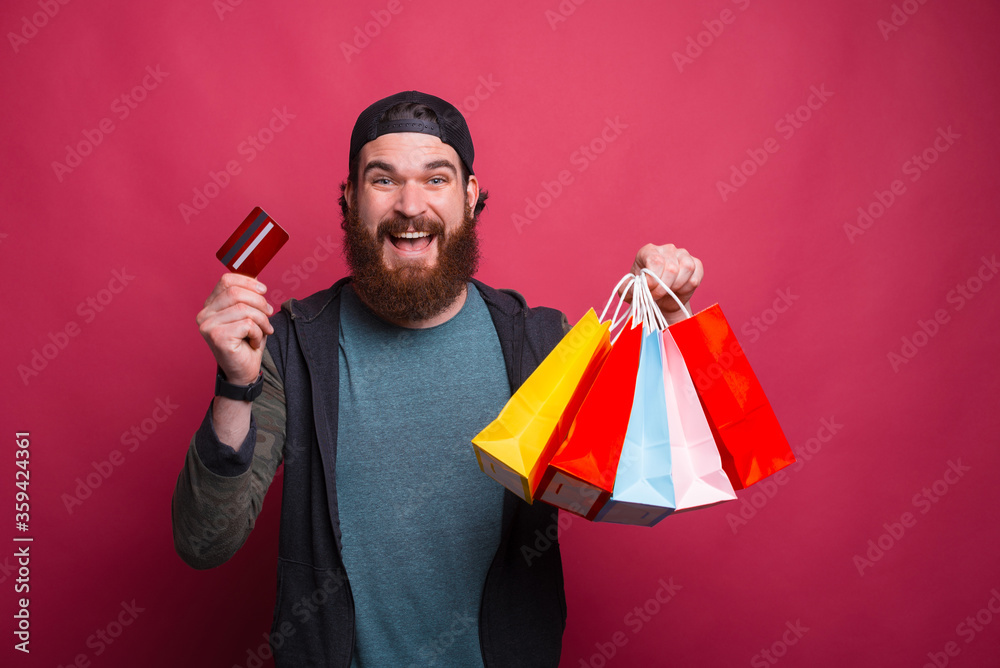 Portrait of happy smiling bearded man holding shopping bags and credit card. Portrait of happy smiling bearded man holding shopping bags and credit card.