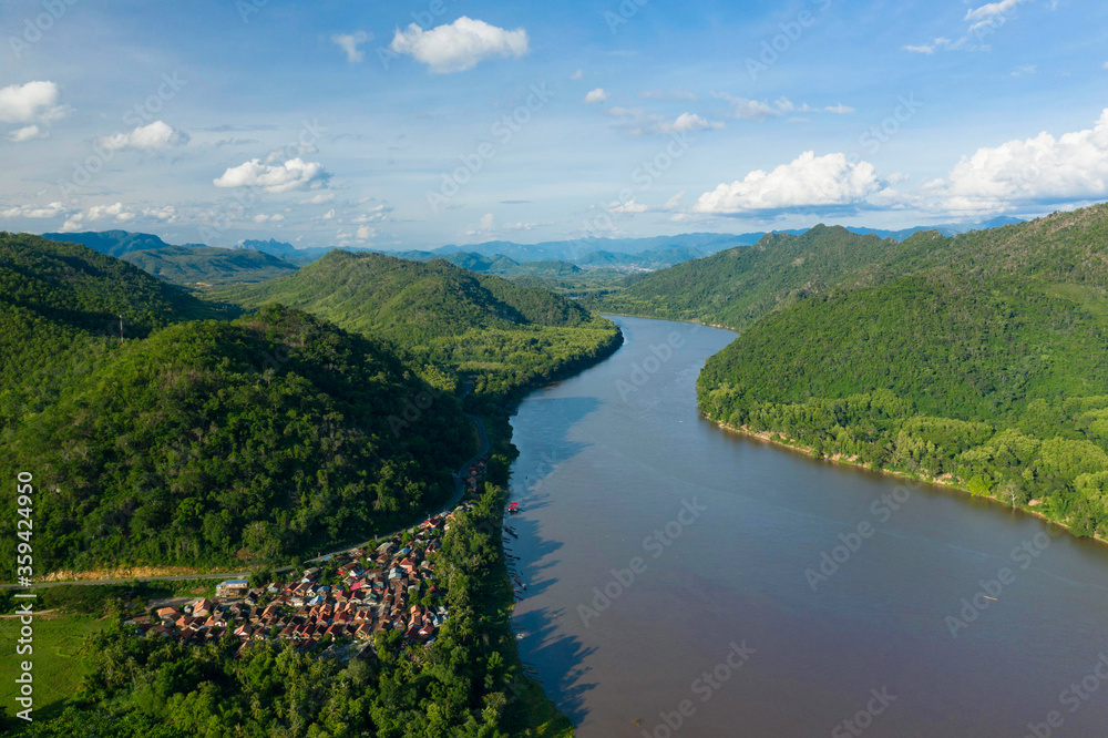 Le fleuve Mékong entouré de montagnes et un petit village traditionnel vers Luang Prabang, au Laos.