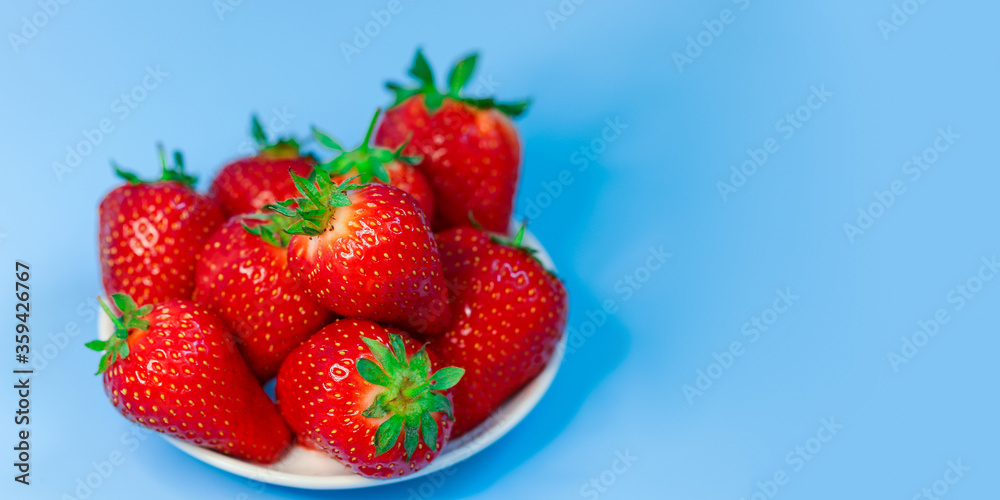 Fresh, ripe, delicious strawberries in a white Cup on a blue background. Free space for text. Background Fresh, ripe, delicious strawberries in a white Cup on a blue background. Free space for text. Background
