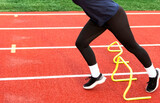 Runners lower body running over yellow mini hurdle