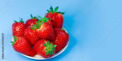 Fresh  ripe  delicious strawberries in a white Cup on a blue background. Free space for text. Background