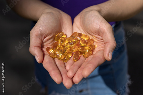 A handful of vitamin d capsules are in women's hands. Blurred background