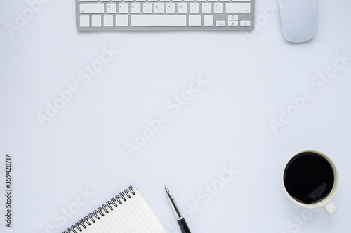 Top view above of White office desk table with keyboard, notebook and coffee cup, mouse with equipment other office supplies. 