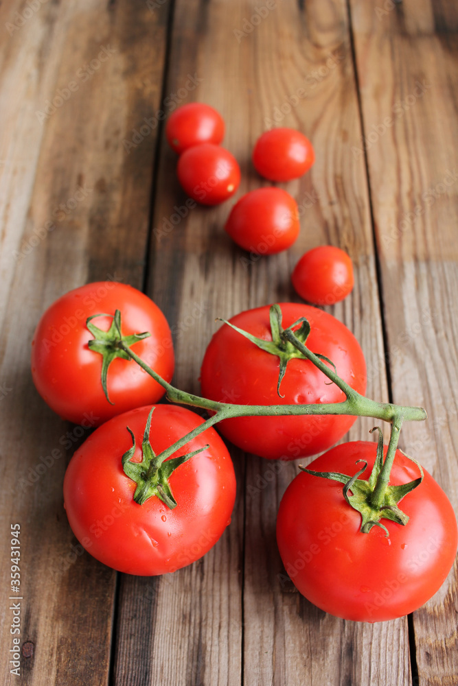 Fresh tomatoes on the vine and cherry tomatoes on rustic wooden table Fresh tomatoes on the vine and cherry tomatoes on rustic wooden table