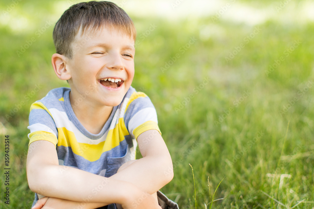 Happy smiling little boy sitting on green grass in park. Happy smiling little boy sitting on green grass in park.