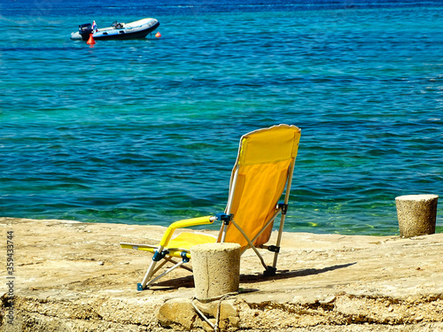 Fototapeta Naklejka Na Ścianę i Meble -  Weniger ist Meer - gelber Liegestuhl am Ufer in Kroatien, Urlaub in Europa