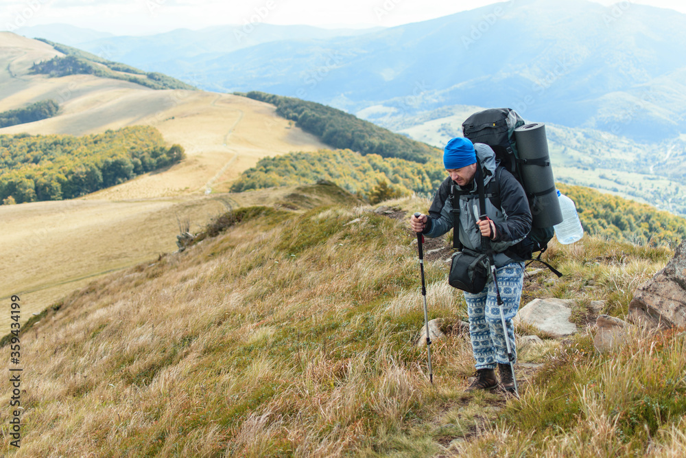 A middle-aged man with a large backpack hiking in the mountains.
