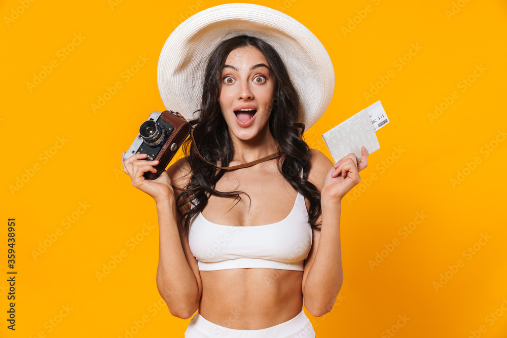 Image of excited woman in swimsuit holding retro camera and passport Image of excited woman in swimsuit holding retro camera and passport
