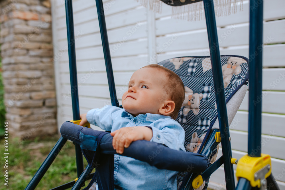 A beautiful caucasian child in a stroller in the yard A beautiful caucasian child in a stroller in the yard