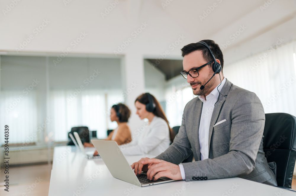 Handsome businessman with headset working on laptop, portrait. Handsome businessman with headset working on laptop, portrait.