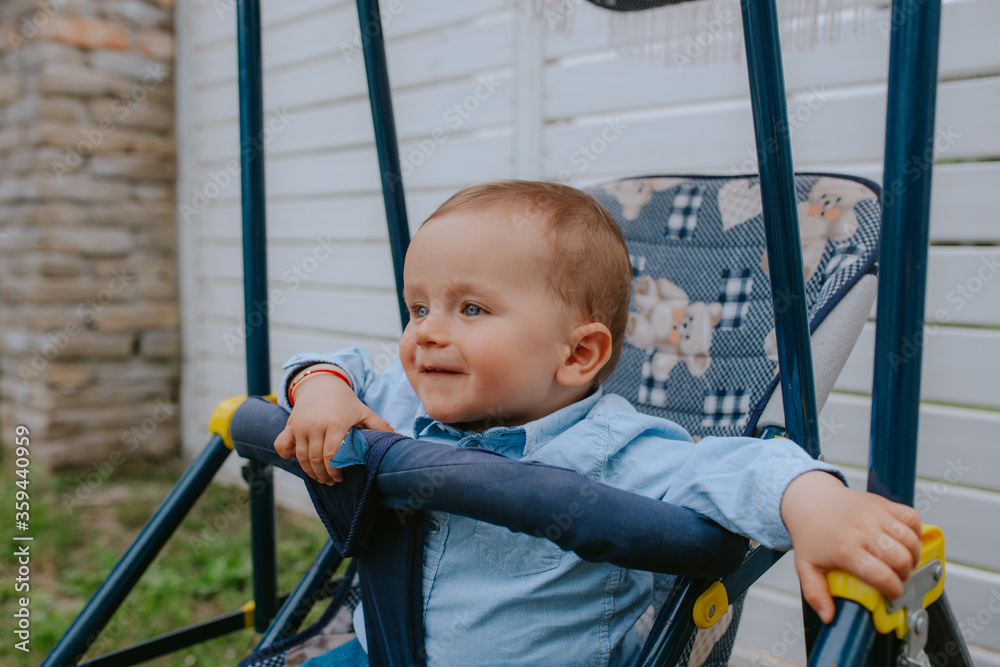 A beautiful caucasian child in a stroller in the yard A beautiful caucasian child in a stroller in the yard