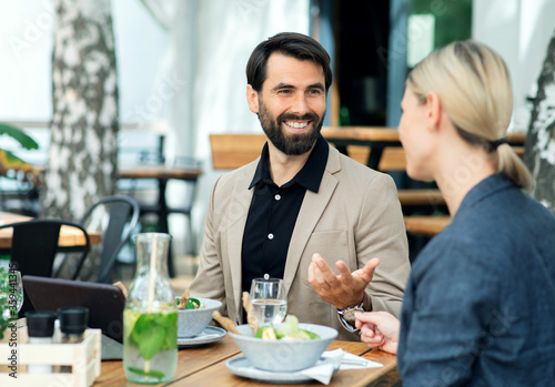 Happy couple sitting outdoors on terrace restaurant  talking.