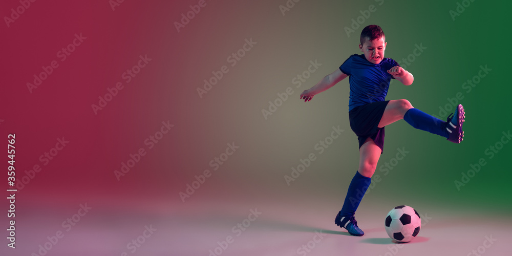 Flyer with copyspace. Teen male football player on gradient background in neon light. Caucasian boy training, practicing on the run, in jump. Concept of sport, competition, winning, motion, action.