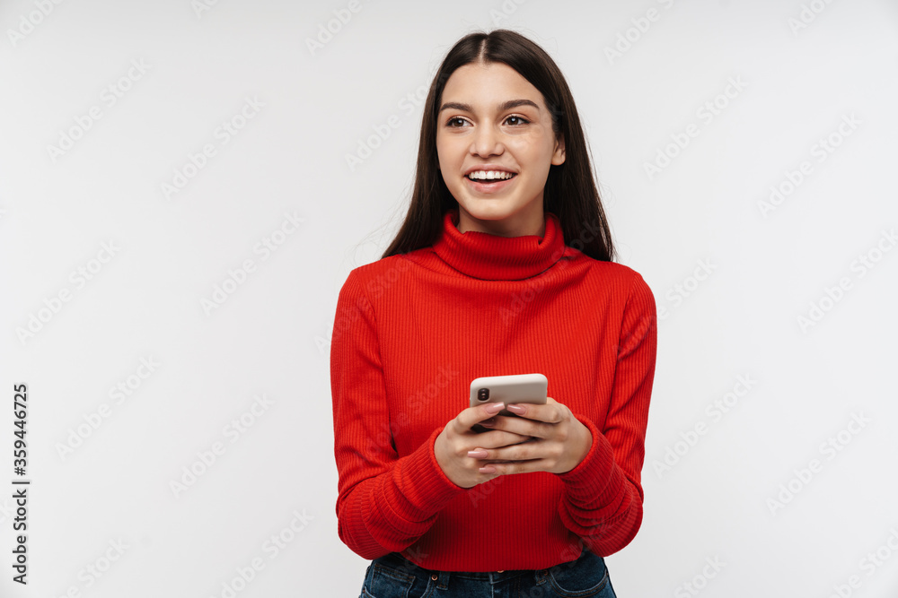 Photo of happy caucasian young woman smiling while using mobile phone Photo of happy caucasian young woman smiling while using mobile phone