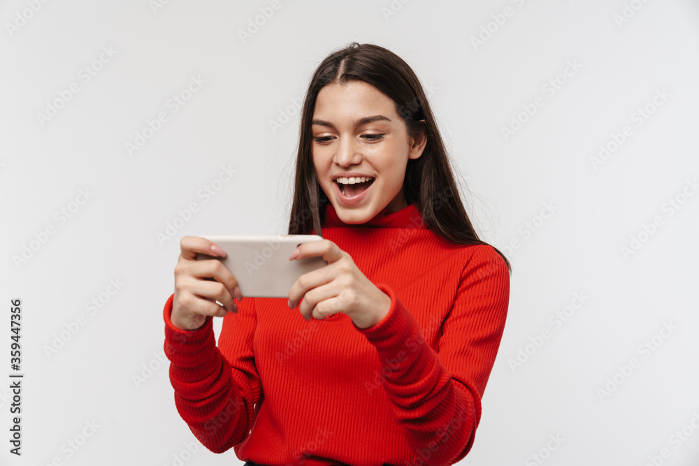 Photo of cheerful woman smiling while playing video game on cellphone Photo of cheerful woman smiling while playing video game on cellphone