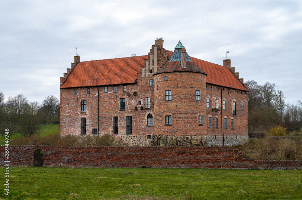 The medieval brick castle is surrounded by a brick wall in a castle garden