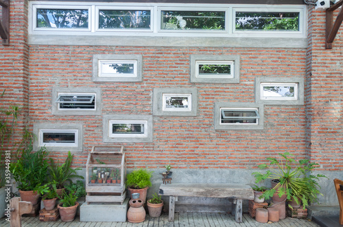Brick wall is decorated with wooden chairs of many plants.