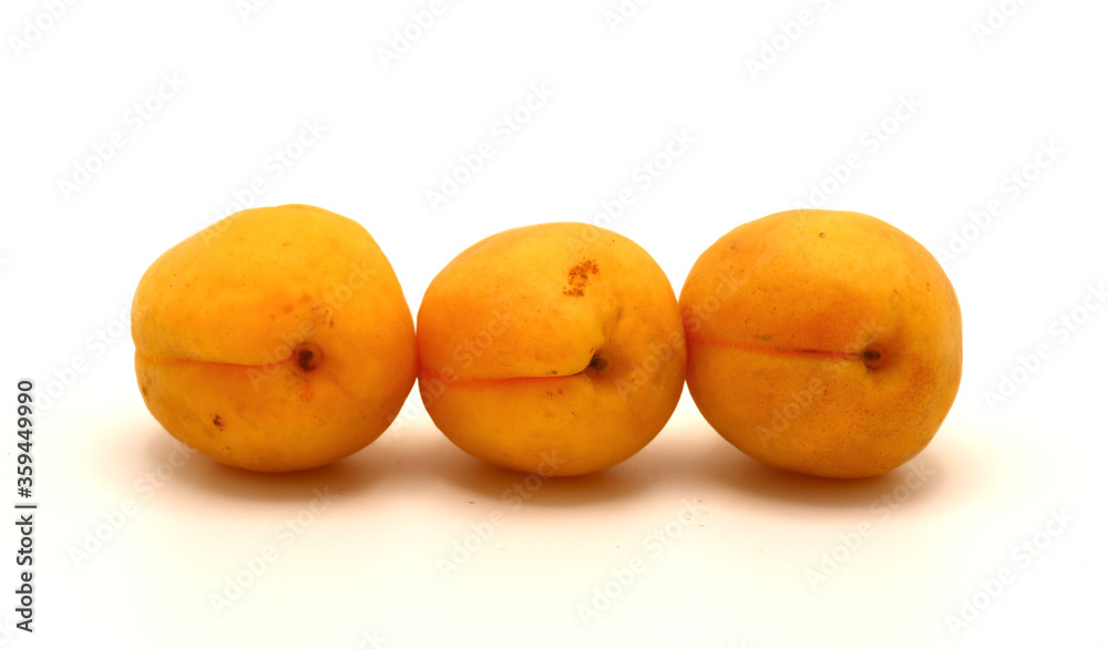 Three apricots on a light background. Natural fruits. Natural color. Close-up. Three apricots on a light background. Natural fruits. Natural color. Close-up.