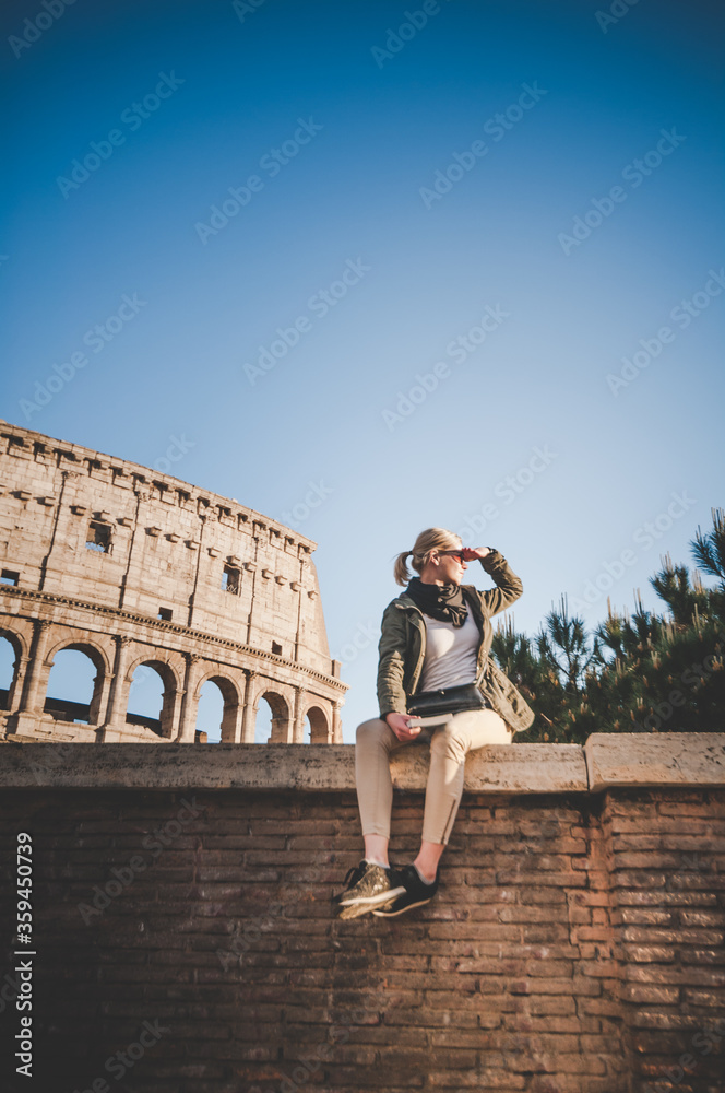 Beautiful girl at autumn sunset in front of the Colosseum in Rome, Italy