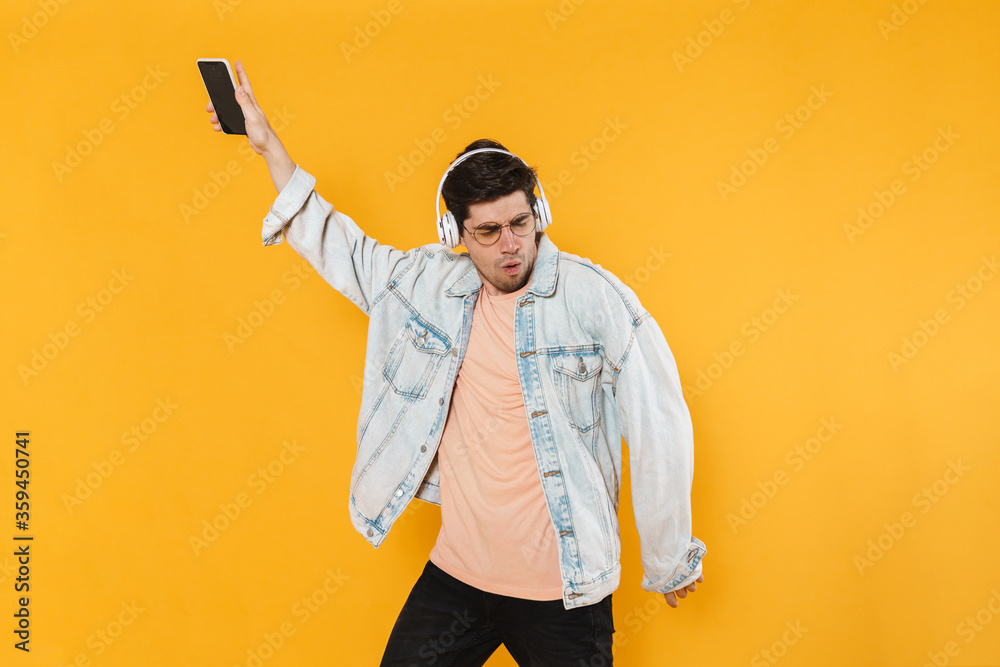 Photo of ecstatic man using mobile phone and headphones while dancing Photo of ecstatic man using mobile phone and headphones while dancing