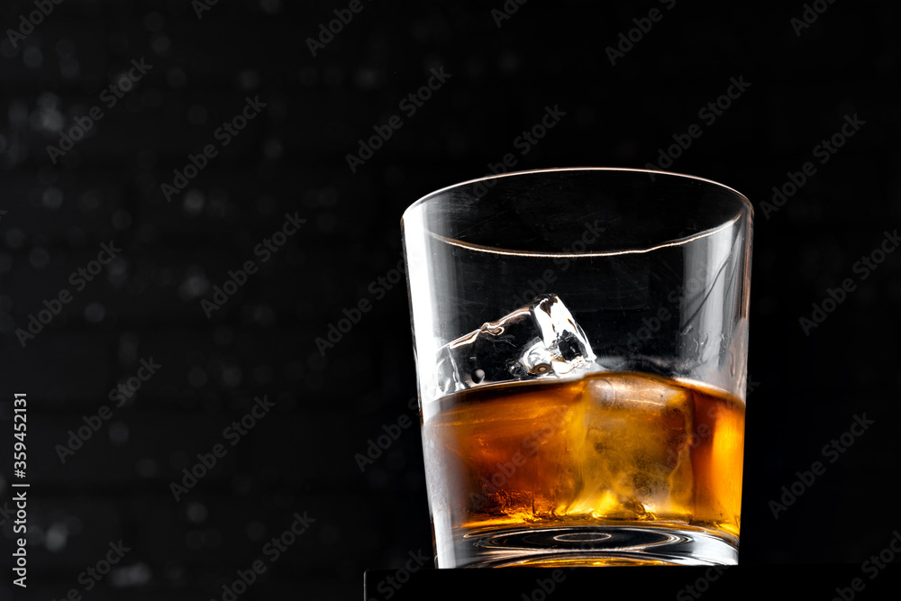 Whisky glass against dark black grunge wall