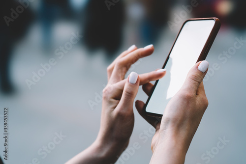 Cropped view of female fingers typing on blank display of smartphone and using 4G internet for installing app on device.Woman's hands holding mobile phone with copy space area for internet content