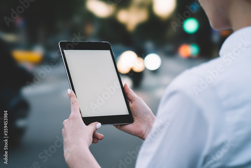 Cropped back view of woman's hands holding digital tablet device with copy space area for your internet content and updating application on gadget using 4G connection on bokeh background