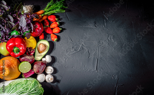 Assortment of fresh fruits and vegetables on dark background. Concept of healthy food. Top view with copy space