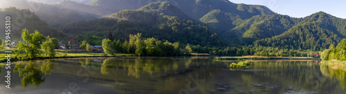 Panorama of a lake or river, in summer, with side lighting and reflections in water