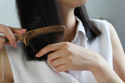 Close up of Asian woman combing hair.
