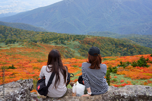 Two young women eating lunch while looking at the beautiful autumn leaves of Mt. Mitsuishi in Iwate Prefecture © GS Planning