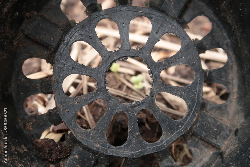 Obraz premium Background of inside an old black plastic plant pot with full of drainage holes on the bottom and dirty with soil.