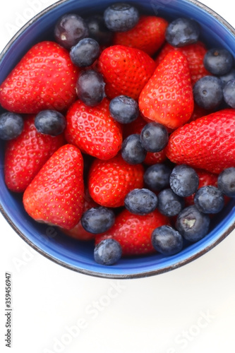 Bowl of blueberries and strawberries on white background. Top view.