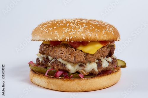 Juicy burger with cucumbers, lettuce, cheese on a white background