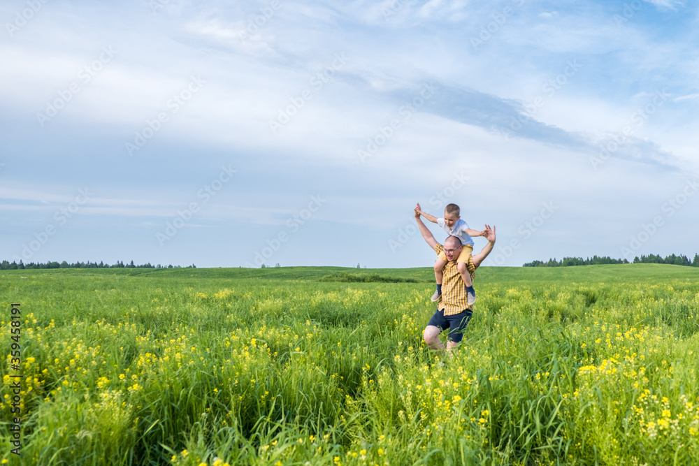 Father and son running and playing on the field at the day time. Concept of friendly family. Great family vacation. Father and son running and playing on the field at the day time. Concept of friendly family. Great family vacation.