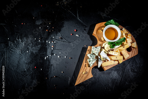 Various kind of cheese served on wooden table, traditional pieces of french and italy cheese on dark background