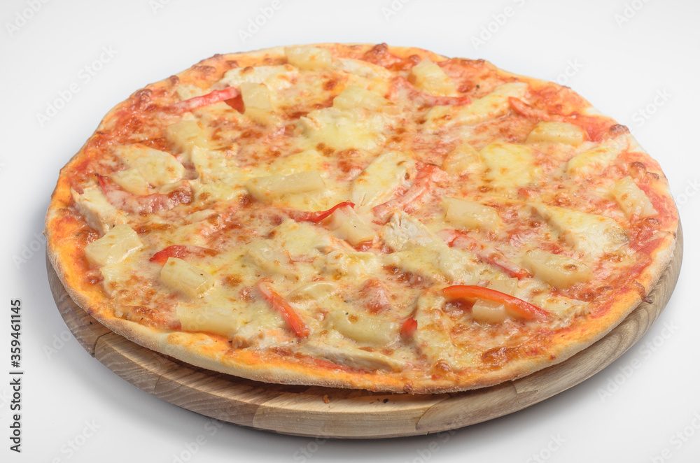 Pizza with chicken and pineapple. Lies on a wooden board on a white background
