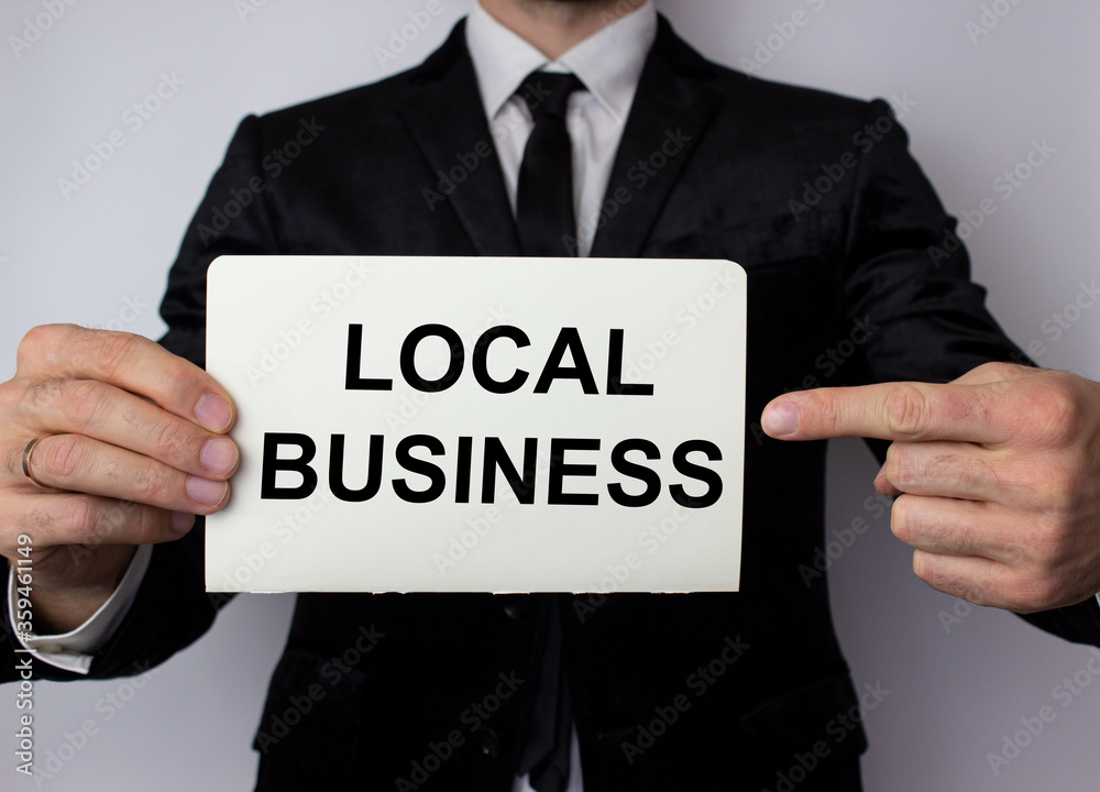 Local business inscription in black letters on a white sheet of paper in the hands of a businessman. Local business support concept. Local business inscription in black letters on a white sheet of paper in the hands of a businessman. Local business support concept.
