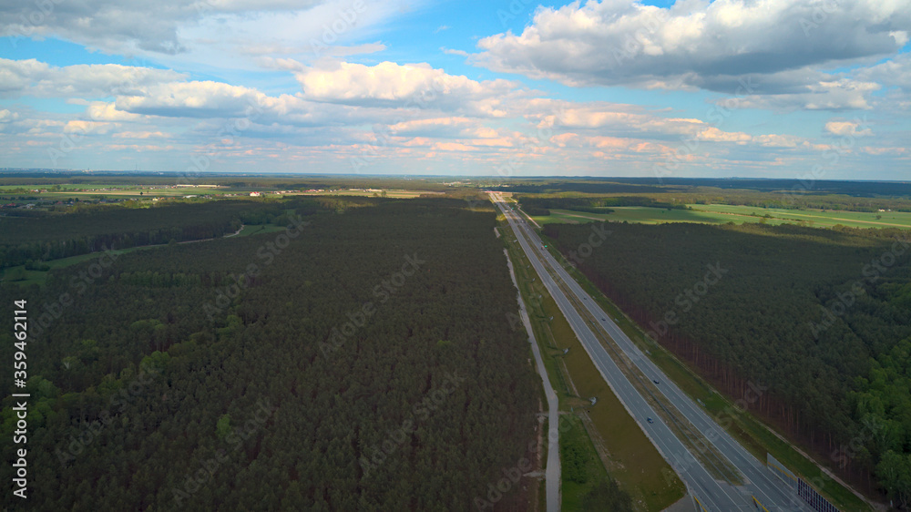 Aerial slant view of a highway surrounded by trees. Late spring in Poland Eastern Europe.