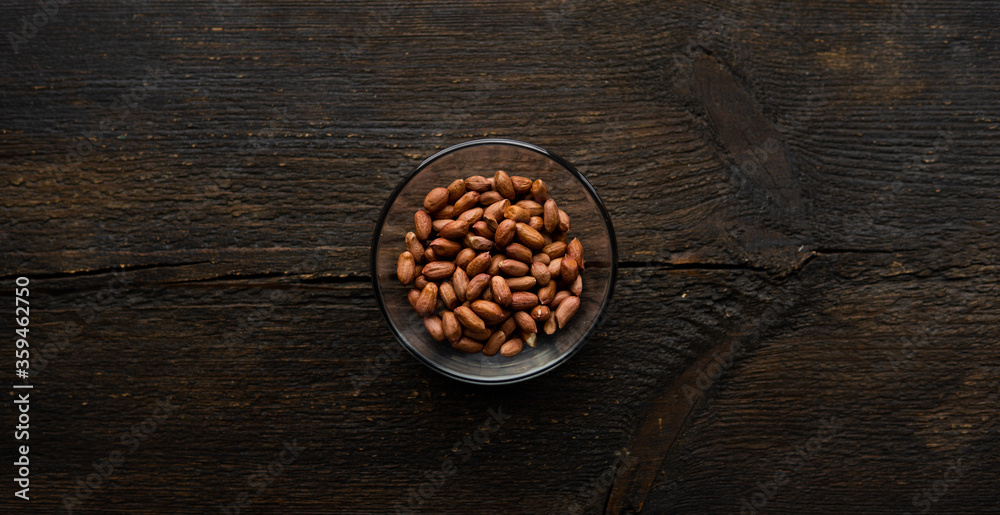 Peanut nuts in a small plate on a vintage wooden table. Peanuts nut is a healthy vegetarian protein nutritious food.